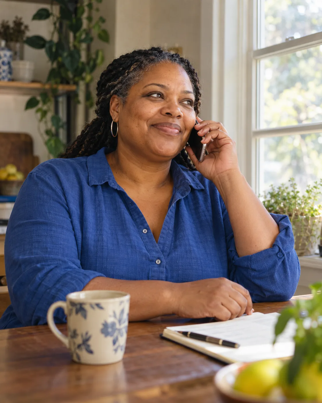 Woman listening to a phone call by a home window.
